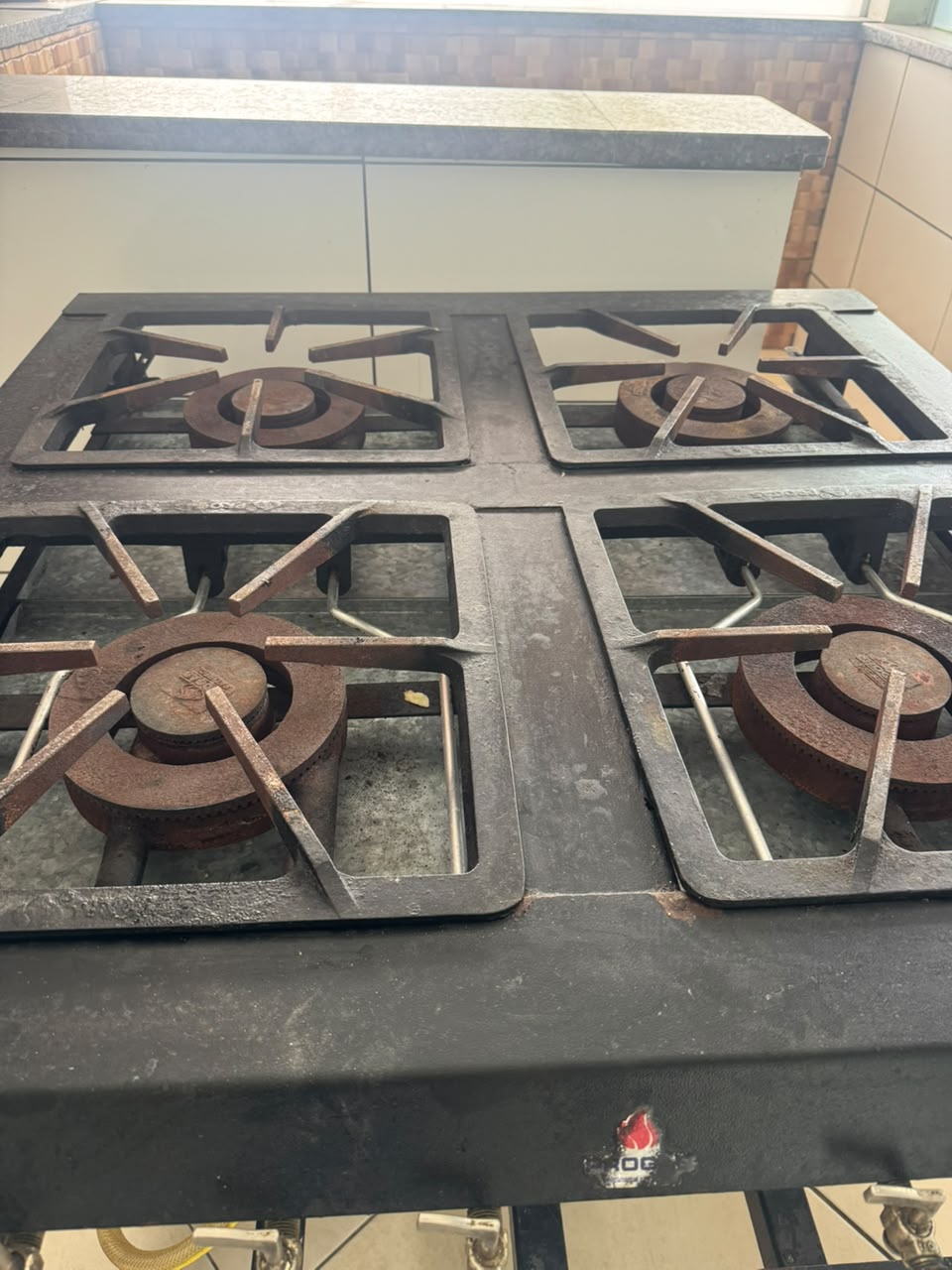 Fogão industrial a gás de quatro bocas na cozinha da chácara