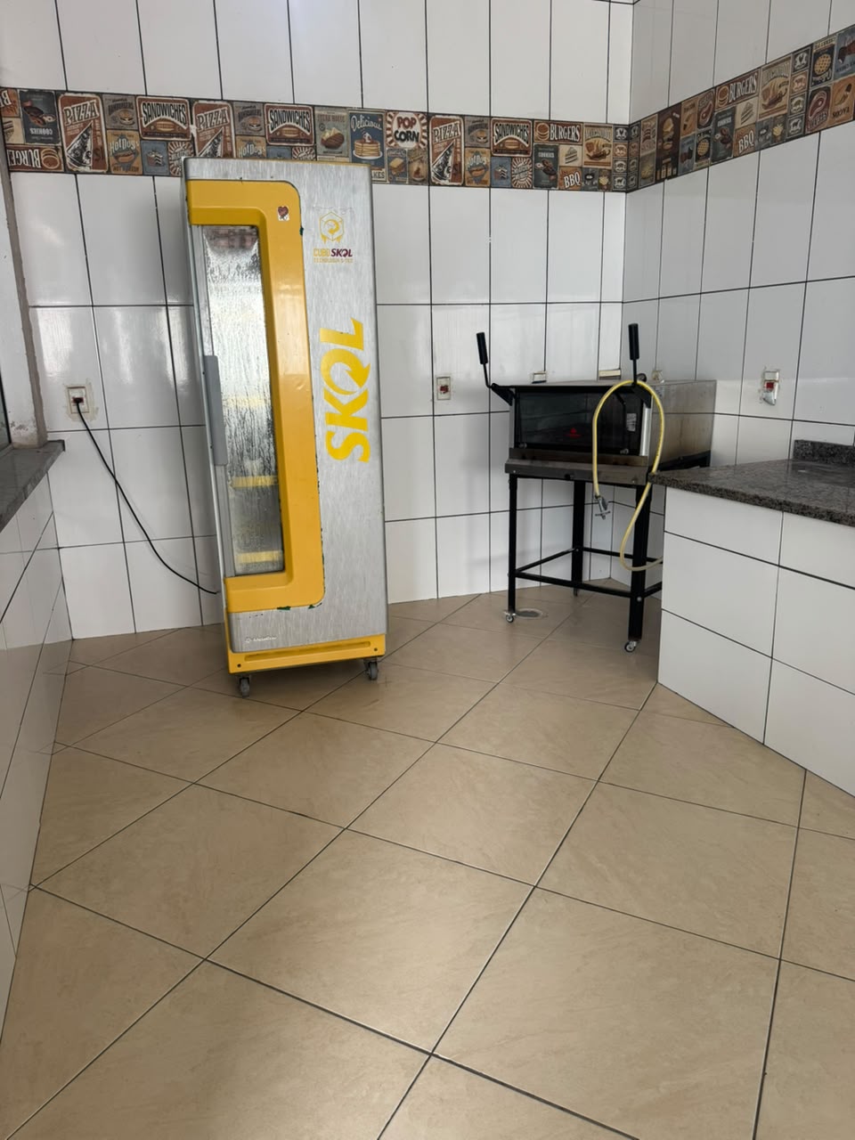 Canto da cozinha com freezer vertical e forno sobre suporte com rodízios