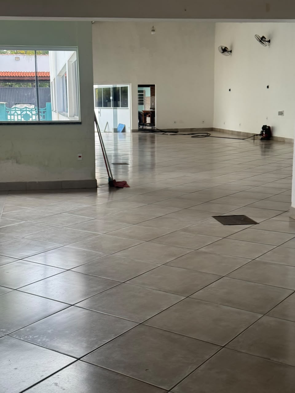 Salão de festa amplo da Chácara Oliver, com piso claro, paredes brancas e janela grande